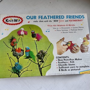 May include: A Knit-Wit craft kit box titled Our Feathered Friends, featuring illustrations of eight colorful pom-pom birds on branches. The box includes text detailing contents like a pom-pon maker, feathers, felt, chenille stems, and yarn.