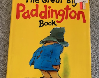 May include: A yellow book cover with the title "The Great Big Paddington Book" by Michael Bond. The cover features a cartoon illustration of Paddington Bear wearing a blue coat and a brown hat.