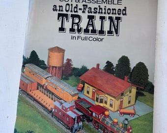 May include: A vintage book cover titled "CUT & ASSEMBLE an Old-Fashioned TRAIN in Full Color" by A.G. Smith. The cover features a colorful illustration of a train, train station, and water tower on tracks.