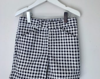 May include: Black and white gingham shorts hanging on a white hanger. The shorts have a classic fit and a cuffed hem.