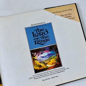 May include: The front cover of a book titled "The Lord of the Rings" film book by J.R.R. Tolkien. The cover features a landscape scene with a river and mountains. The book is published by Ballantine, New York.
