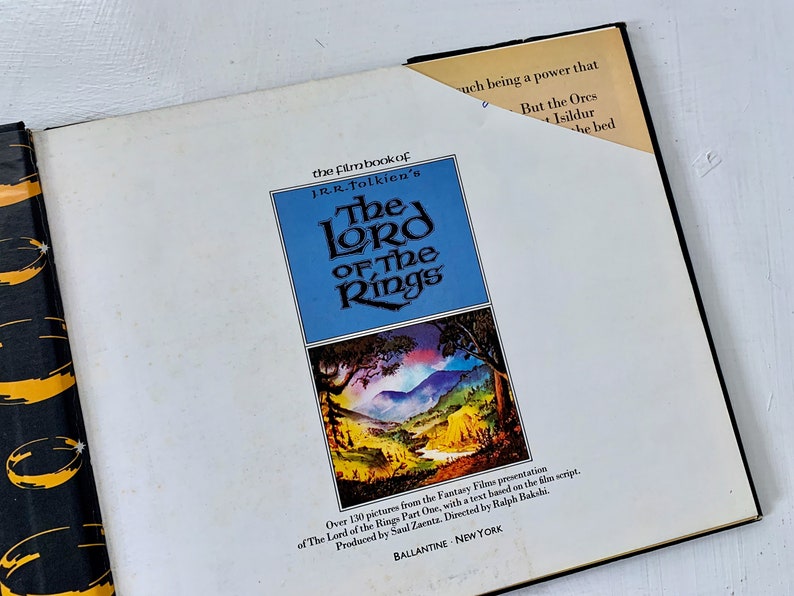 May include: The front cover of a book titled "The Lord of the Rings" film book by J.R.R. Tolkien. The cover features a landscape scene with a river and mountains. The book is published by Ballantine, New York.