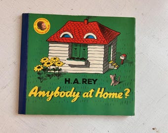 May include: A children's book titled Anybody at Home? by H.A. Rey. The cover features a white house with a red roof, green shutters, and a window box on a green lawn. Yellow sunflowers, a small cat, and a mailbox are visible. A circular badge shows a monkey.
