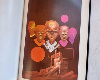 May include: An open book page featuring a surreal illustration with five distinct, colorful alien-like heads floating above a stone architectural structure. The text The Best of F&SF is visible at the top left, and the number 23 is at the bottom.