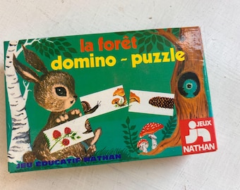 May include: A rectangular game box titled la forêt domino - puzzle featuring a brown rabbit, a tree, mushrooms, and forest elements on a green background. The box includes the Jeux Nathan logo and displays illustrations of snails, berries, and pinecones.
