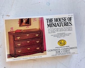 May include: A white rectangular box for The House of Miniatures Chippendale 3 drawer chest kit. The box features an image of a brown wooden chest with gold hardware, text detailing the contents, and the scale of 1 inch to 1 foot.