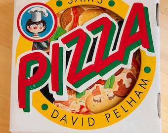 May include: A square white cardboard box featuring a colorful graphic of a pizza. The text reads SAM'S PIZZA and DAVID PELHAM. A circular illustration shows a cartoon chef in a white hat. The design uses red, green, yellow, and black colors.