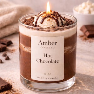 Hot chocolate candle in a clear glass jar designed to look like a warm cup of cocoa, topped with realistic whipped cream wax and chocolate drizzle, handmade soy candle from Amber Candle Co.
