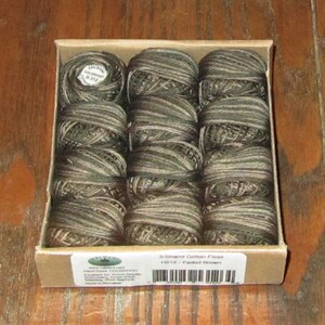 May include: A box of 12 spools of 3-strand cotton floss in a faded brown color. The box is labeled "3-Strand Cotton Floss H212 - Faded Brown".