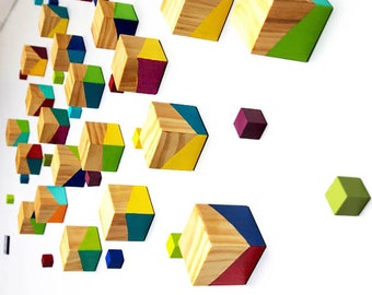 Puede incluir: Una instalación de arte de pared con cubos de madera pintados en varios colores, incluyendo amarillo, verde, azul, rojo y morado. Los cubos están dispuestos en un patrón geométrico, creando un diseño moderno y abstracto.