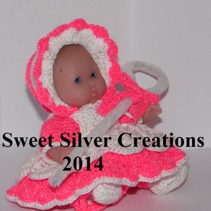 Könnte beinhalten: Ein pinkfarbenes und weißes Häkel-Puppenkleid mit einer weißen Häkelmütze. Die Puppe hält einen weißen Pfeifenreiniger. Der Text "Sweet Silver Creations 2014" ist im Bild zu sehen.