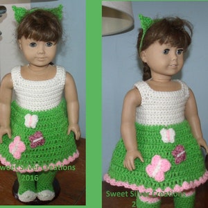May include: A doll wearing a handmade crochet outfit. The outfit includes a white top, a green skirt with pink and white butterfly appliques, and matching green leggings. A green headband with cat ears completes the look. The text "Sweet Silver Creations 2016" is visible.