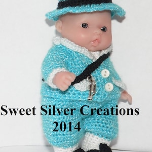 Könnte beinhalten: Eine gehäkelte Puppe in einem blauen und weißen Outfit mit einem schwarzen Hut und einer silbernen Trompete. Die Puppe steht auf einer weißen Oberfläche. Sweet Silver Creations 2014.