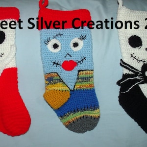 Puede incluir: Tres calcetines de Navidad tejidos a crochet con personajes de Pesadilla antes de Navidad. Los calcetines son rojos, azules y negros con detalles blancos. Los personajes son Jack Skellington, Sally y Oogie Boogie. El texto "Sweet Silver Creations 2015" es visible en la parte superior de la imagen.