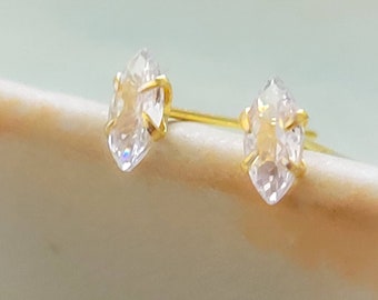 May include: A pair of gold earrings with clear marquise-shaped stones.