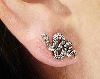 May include: Silver snake earring with a detailed design. The snake is curled up and has a textured surface.