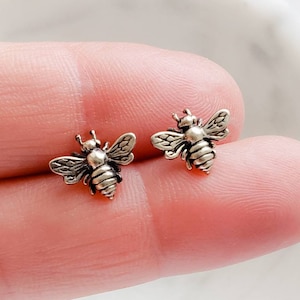 May include: A pair of silver bee stud earrings. The bees are detailed with wings and a body.