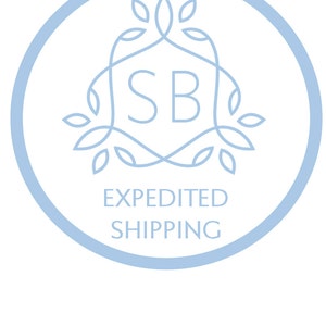 May include: A light blue circle with a stylized floral design and the letters "SB" in the center. The text "EXPEDITED SHIPPING" is below the design.