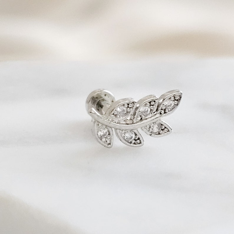 May include: Silver leaf-shaped earring with clear cubic zirconia stones.