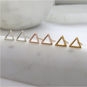 May include: A set of six triangle stud earrings in three different metal finishes: silver, rose gold, and gold.