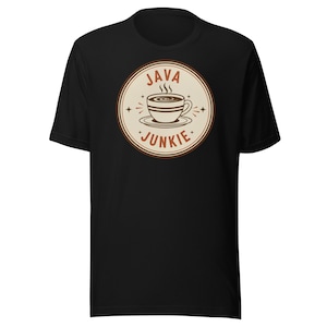 May include: Black t-shirt with a circular coffee-themed graphic. The design features a coffee cup and the words "JAVA JUNKIE" in brown and beige. Steam rises from the cup. The t-shirt has a crew neck.