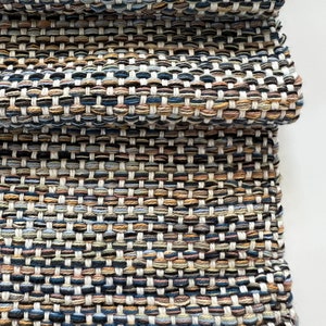 Puede incluir: Una alfombra tejida con un patrón texturizado en tonos de azul, marrón, beige y blanco.