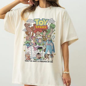 Puede incluir: Camiseta color crema con un gr&aacute;fico colorido de personajes de la pel&iacute;cula animada "Toy Story". El dise&ntilde;o incluye el t&iacute;tulo de la pel&iacute;cula y la frase "You've Got a Friend in Me".