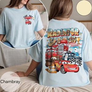 Puede incluir: Camiseta azul claro con un gr&aacute;fico colorido de personajes de la pel&iacute;cula Cars. La parte trasera de la camiseta muestra "Radiator Springs" y "Lightning McQueen". La parte delantera tiene un gr&aacute;fico m&aacute;s peque&ntilde;o con un cami&oacute;n de bomberos.