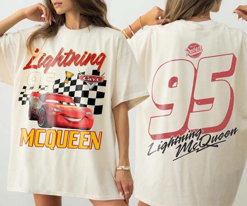 May include: Cream-colored t-shirt featuring a graphic of Lightning McQueen from the Cars movie. The front design includes the text "Lightning McQueen 95" with a checkered flag and trophy. The back displays a large "95" and "Lightning McQueen" text.