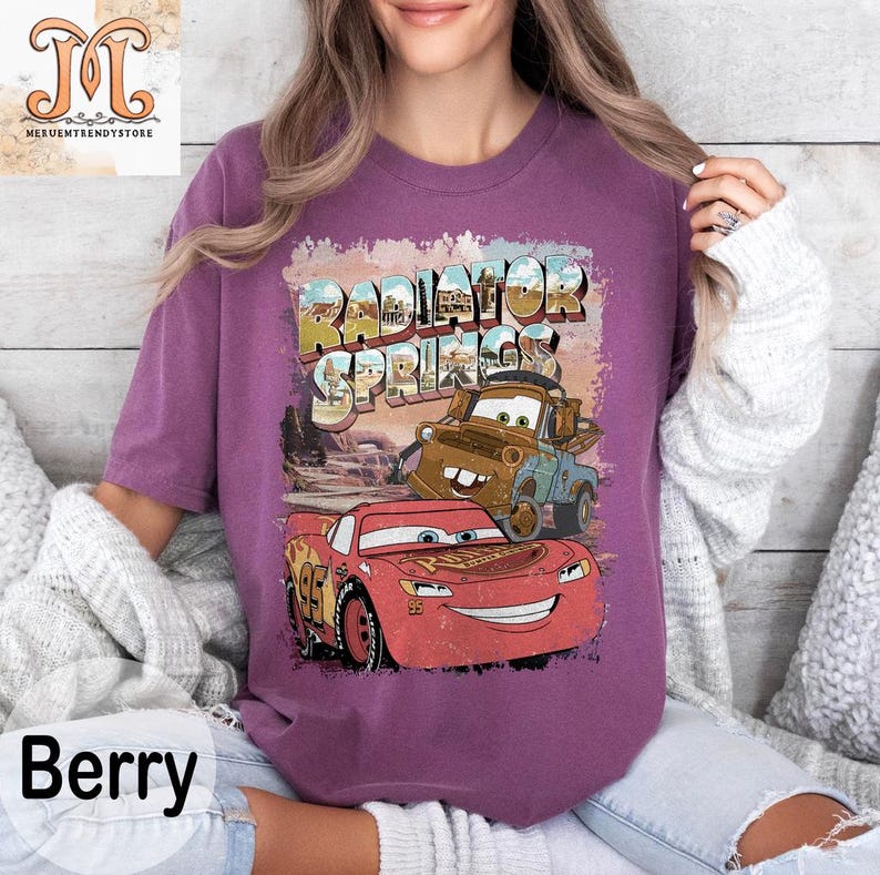 May include: Purple t-shirt with a vintage-style graphic of Lightning McQueen and Mater from the movie Cars. The graphic includes the text "Radiator Springs".