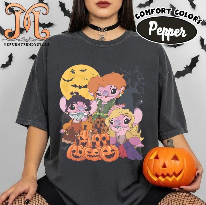 May include: Dark gray Comfort Colors t-shirt featuring a Halloween-themed graphic. The design includes cartoon characters, jack-o'-lanterns, a full moon, and bats. The shirt also has the text "Pepper" and "Comfort Colors".