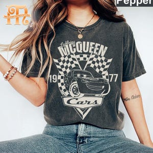 May include: A gray t-shirt with a vintage-style graphic of Lightning McQueen from the Disney Pixar movie Cars. The graphic includes the text "Lightning McQueen", "Cars", and the numbers "19" and "77".