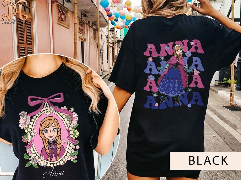 May include: Two black t-shirts with different Anna from Frozen designs. One shirt features a cartoon image of Anna in a pink frame with flowers and the word "Anna" below. The other shirt has a repeated image of Anna in a purple dress with the word "Anna" in a retro font.