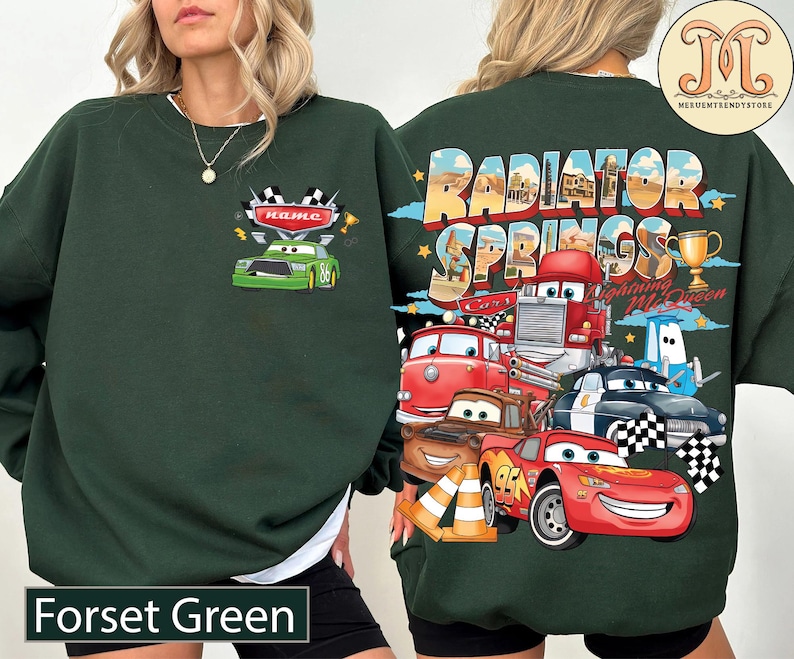 Puede incluir: Sudadera verde oscuro con un dise&ntilde;o de coche de carreras verde y la palabra "name" en la parte delantera. La parte trasera presenta un dise&ntilde;o colorido de personajes y las palabras "Radiator Springs Cars Lightning McQueen". El texto "Forset Green" est&aacute; en la parte inferior.