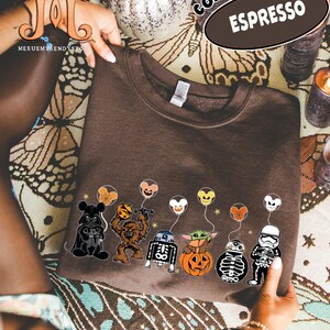 Op de afbeelding: Bruin sweatshirt met een rij Star Wars-personages die ballonnen vasthouden. De ballonnen hebben gezichten die ge&iuml;nspireerd zijn op Mickey Mouse. Op de trui staan de woorden "Comfort Colors" en "Espresso".