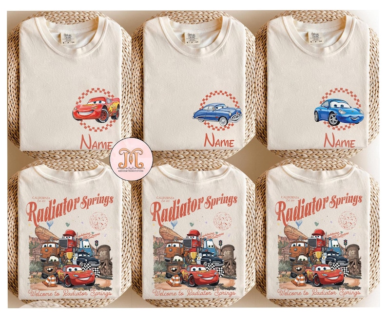 Op de afbeelding: Cr&egrave;mekleurige t-shirts met cartoon autographics. Sommige shirts hebben een enkel auto-ontwerp met het naamveld, terwijl andere een grotere afbeelding tonen met de tekst "Radiator Springs" en "Welcome to Radiator Springs".