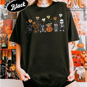 Op de afbeelding: Zwart T-shirt met een afbeelding van Star Wars-personages als Halloween-decoraties. De personages zijn onder meer Mickey Mouse, Chewbacca, R2-D2, Baby Yoda, een pompoen, een skelet en een Stormtrooper, elk met een ballon. De woorden "COMFORT COLORS" en "Black" zijn gedrukt.