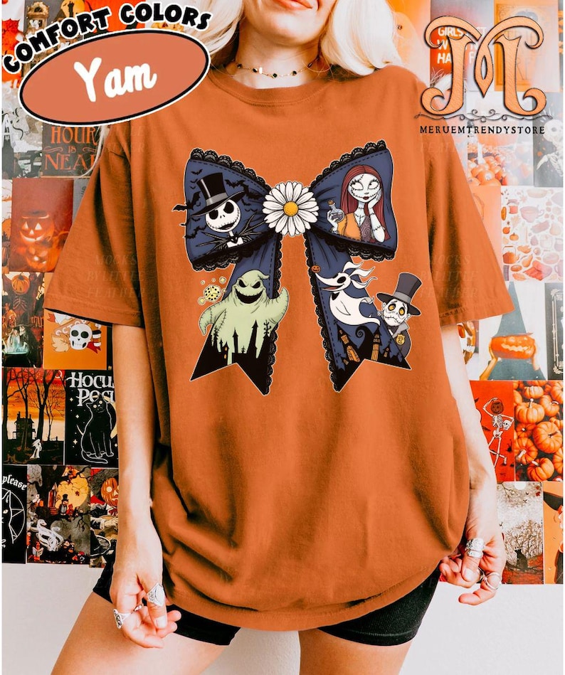 Peut inclure: T-shirt orange Comfort Colors avec un grand n&oelig;ud bleu orn&eacute; de personnages de L'&Eacute;trange No&euml;l de Monsieur Jack. Le n&oelig;ud a une marguerite blanche au centre et une bordure en dentelle noire. Le t-shirt porte &eacute;galement le mot "Yam" dans un ovale blanc.