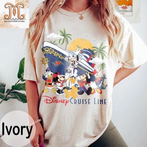 May include: Ivory-colored t-shirt featuring a Disney Cruise Line design. The graphic includes Mickey Mouse, Minnie Mouse, Donald Duck, and other characters on a cruise ship with palm trees and a sunset. The text "Disney Cruise Line" is printed below the characters.