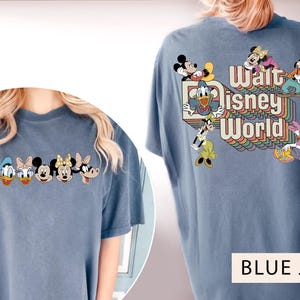 Puede incluir: Una camiseta azul con un gr&aacute;fico de Mickey Mouse y otros personajes de Disney. El texto "Walt Disney World" est&aacute; impreso en colores arco&iacute;ris en la parte posterior de la camiseta.