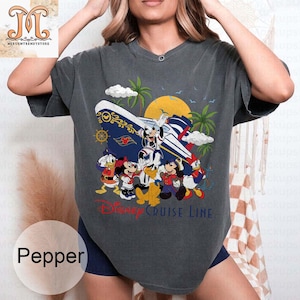 May include: Dark gray t-shirt featuring a colorful graphic of Disney characters on a cruise ship, with palm trees and a sun in the background. The text "Disney Cruise Line" is printed below the characters. The shirt is a Pepper color.