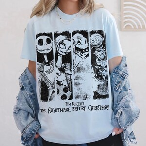 以下が含まれることがあります： ティム・バートンの『ナイトメアー・ビフォア・クリスマス』のキャラクターが描かれた、黒と白のグラフィックプリント付きのライトブルーのTシャツ。デザインには、ジャック・スケリントン、サリー、ウギー・ブギー、ロック、ショック、バレルの4つの垂直パネルが含まれています。
