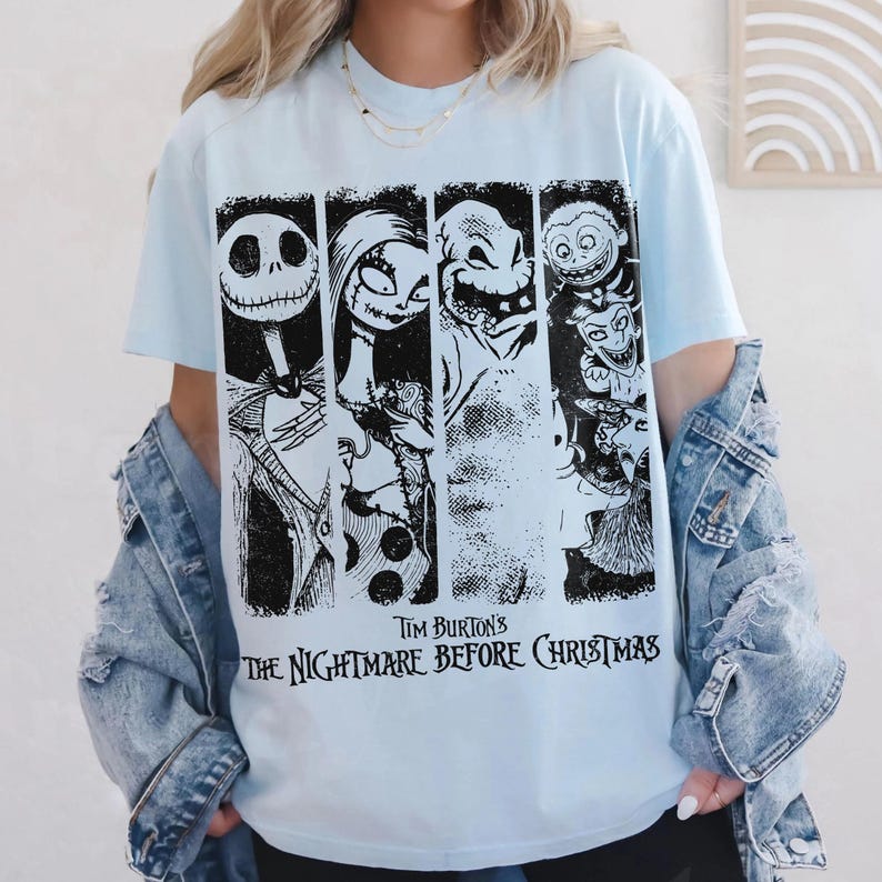 以下が含まれることがあります： ティム・バートンの『ナイトメアー・ビフォア・クリスマス』のキャラクターが描かれた、黒と白のグラフィックプリント付きのライトブルーのTシャツ。デザインには、ジャック・スケリントン、サリー、ウギー・ブギー、ロック、ショック、バレルの4つの垂直パネルが含まれています。