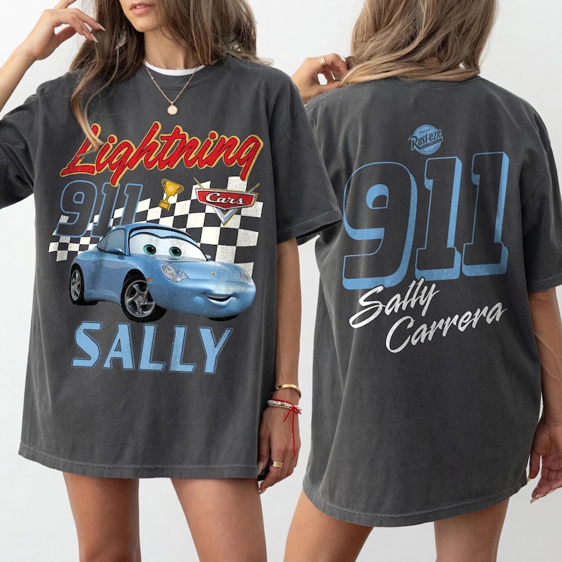 May include: Dark gray t-shirt featuring a blue cartoon car with the text "Lightning 911 Cars" and "SALLY" on the front. The back of the shirt displays "911 Sally Carrera" in blue and white.