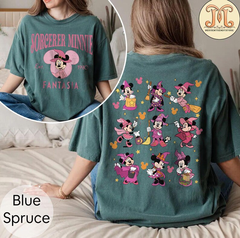 May include: A teal blue t-shirt with a pink and white graphic of Mickey Mouse as a sorcerer on the front. The back of the shirt features a pattern of Mickey Mouse dressed as a witch in various poses.
