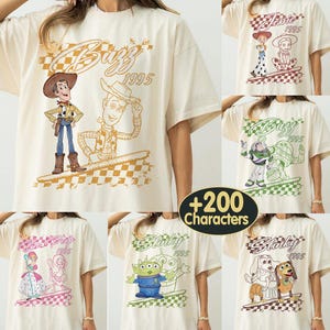 K&ouml;nnte beinhalten: Cremefarbene T-Shirts mit verschiedenen Toy Story-Charaktergrafiken. Jedes Shirt hat ein anderes Design, darunter Woody, Buzz Lightyear, Jessie und Slinky, mit dem Jahr 1995. Die Designs sind auf einem karierten Hintergrund gedruckt.