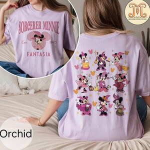 May include: A purple t-shirt with a graphic of Sorcerer Minnie Mouse on the front and a graphic of multiple Sorcerer Minnie Mouse characters on the back. The text "Sorcerer Minnie Est. 1940 Fantasia" is printed on the front of the shirt.
