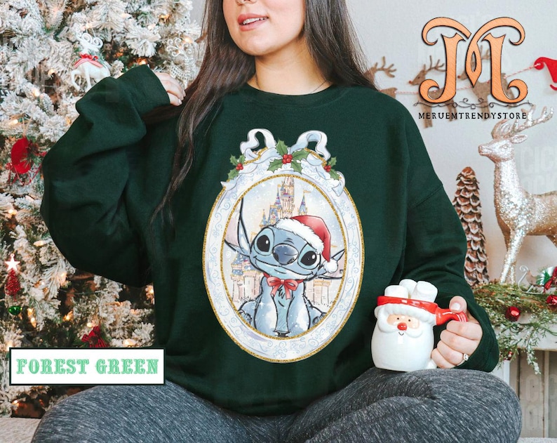 May include: Forest green sweatshirt featuring a cartoon character in a Santa hat, inside an oval frame with a castle background. The sweatshirt has the text "FOREST GREEN" at the bottom. A Santa mug is held in the hand.