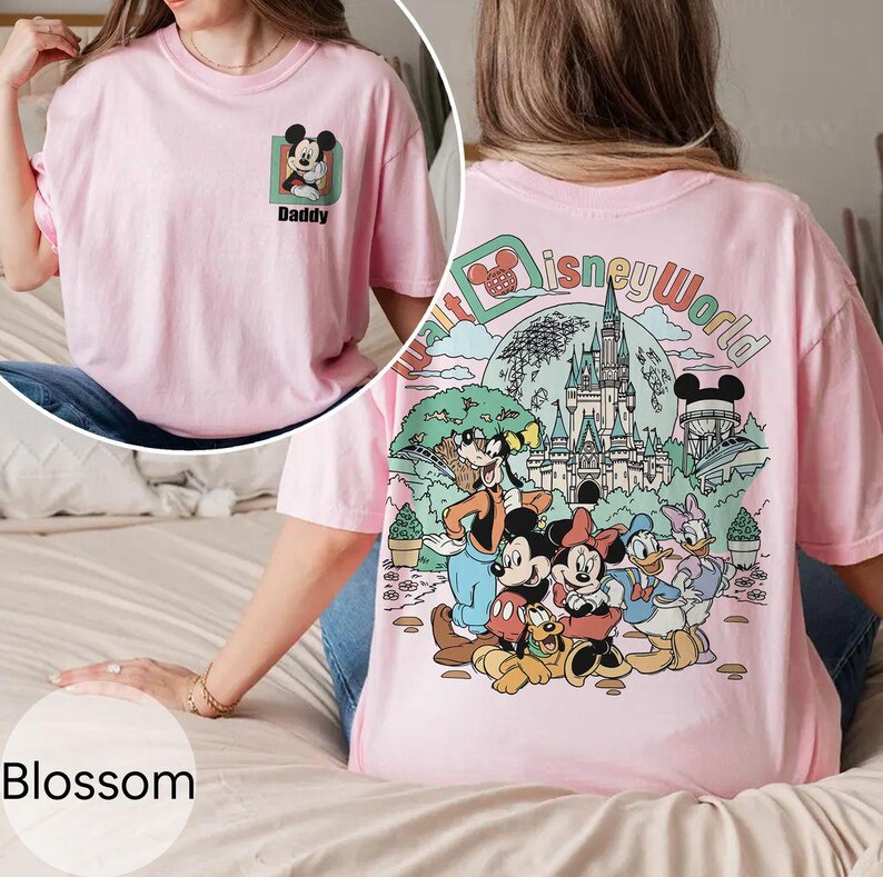 May include: Pink t-shirt with a Mickey Mouse graphic and the word "Daddy" on the front, and a large Disney World graphic on the back. The shirt has short sleeves and a crew neck.