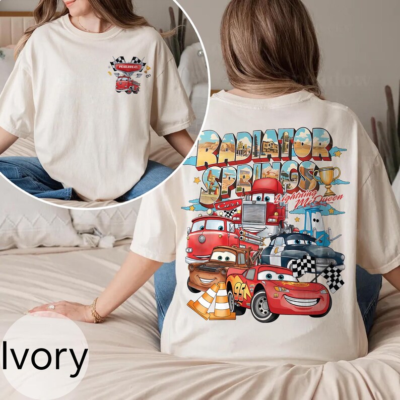 Puede incluir: Camiseta de color marfil con un gr&aacute;fico colorido de personajes de la pel&iacute;cula Cars, incluyendo a Rayo McQueen y Mate, con el texto "Radiator Springs". La parte delantera de la camiseta tiene un peque&ntilde;o gr&aacute;fico de un cami&oacute;n rojo.